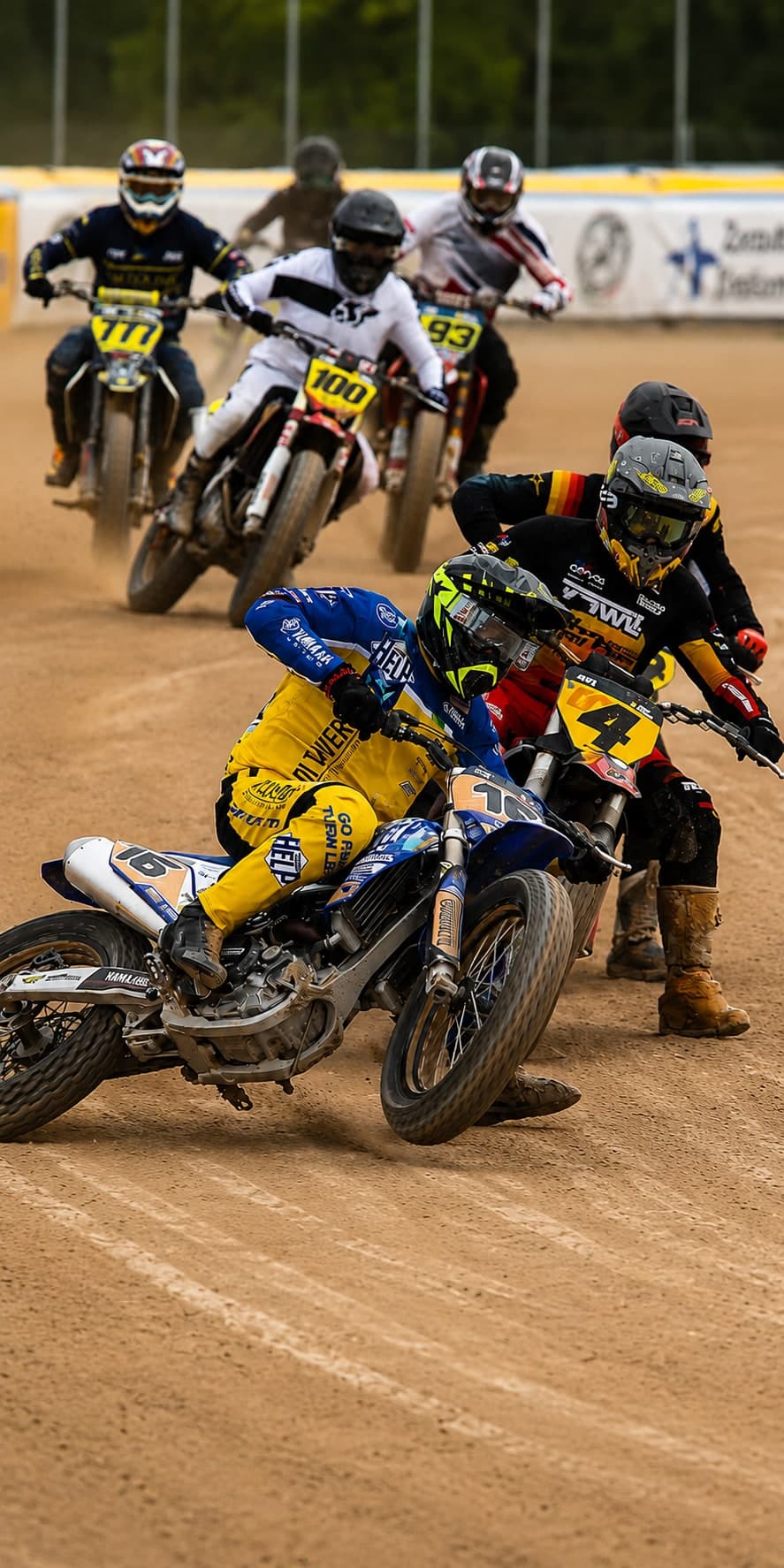 Pilotos de flat track deslizando en el óvalo de tierra