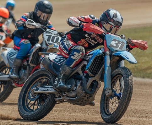 Grupo de pilotos de flat track entrando a la curva sobre la tierra
